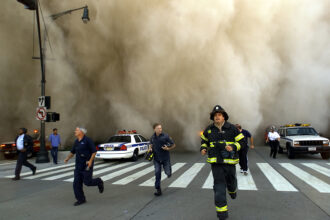 Police and firefighters run away from a toxic dust cloud caused by the World Trade Center’s Tower One collapse in New York City on Sept. 11, 2001. Credit: Jose Jimenez/Primera Hora/Getty Images