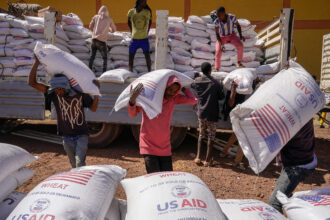 Volunteers unload sacks of wheat flour from USAID at a camp for internally displaced people on Dec. 17, 2021, in Bahir Dar, Ethiopia. Credit: J. Countess/Getty Images
