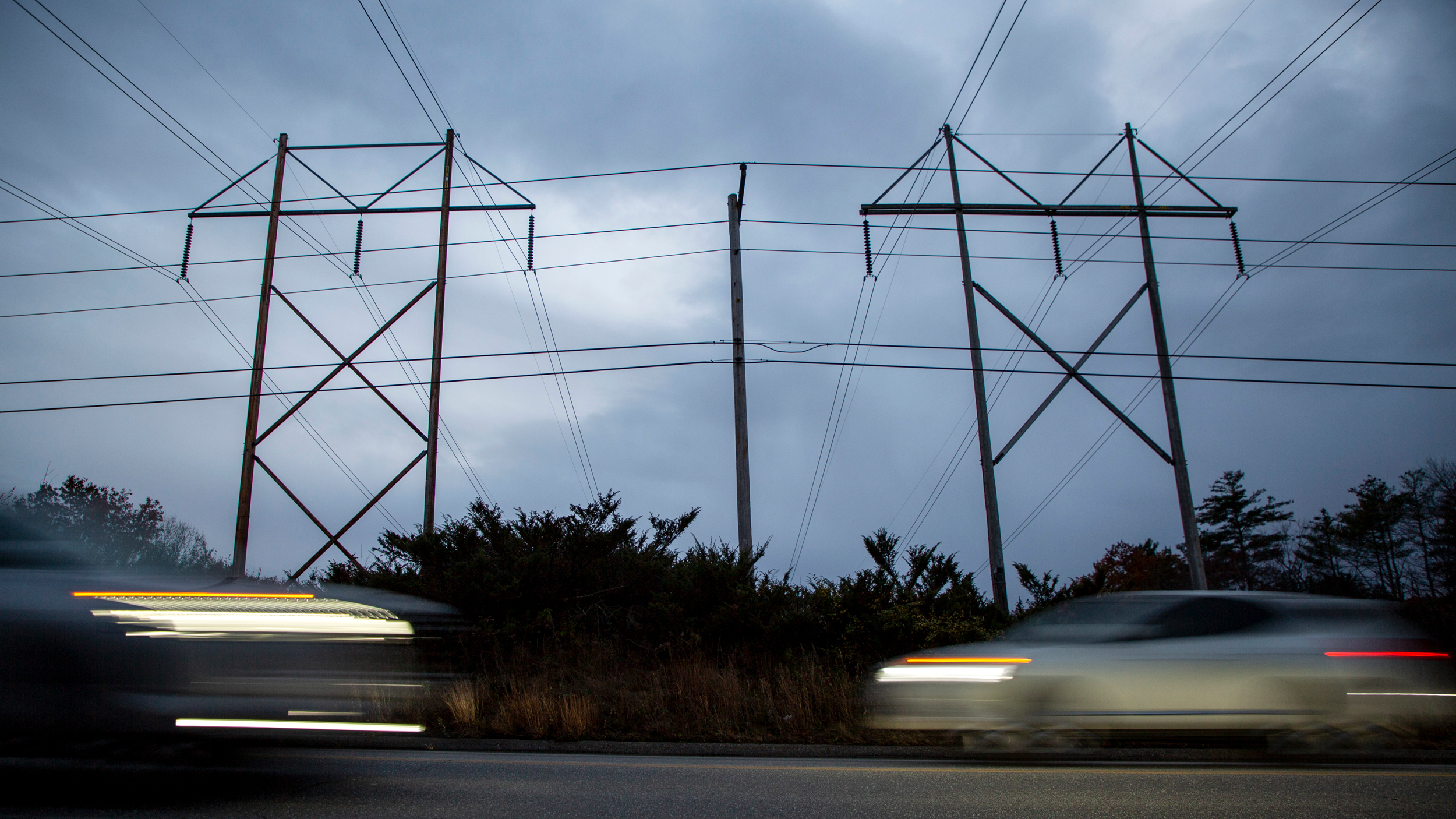 Cars drive under transmission lines at dusk on Route 117 in Hollis Center, Maine. Credit: Andrew Dickinson/The Washington Post via Getty Images