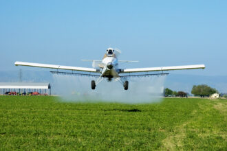 The crop duster spraying a field is flying low in the direction of the photographer