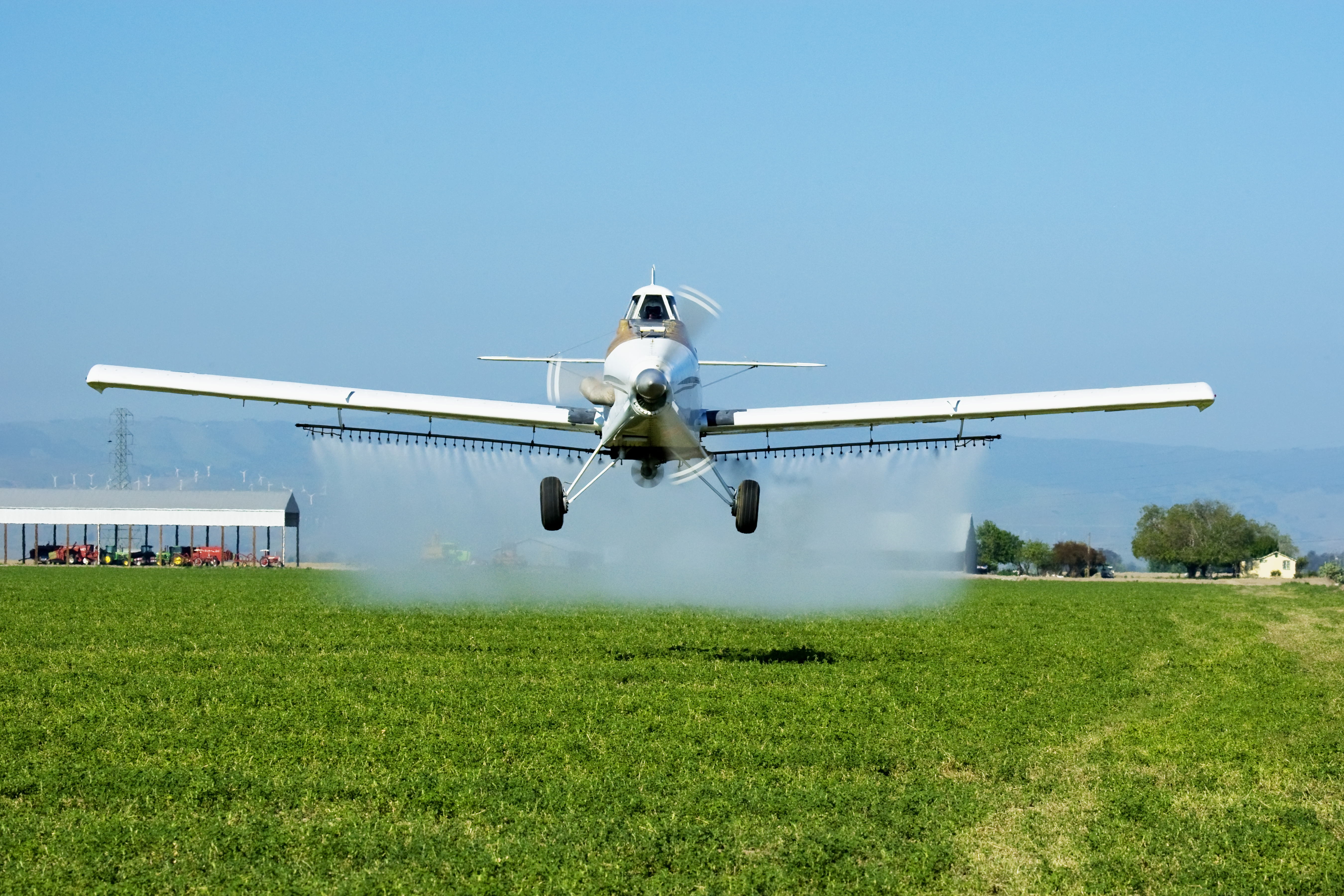 The crop duster spraying a field is flying low in the direction of the photographer