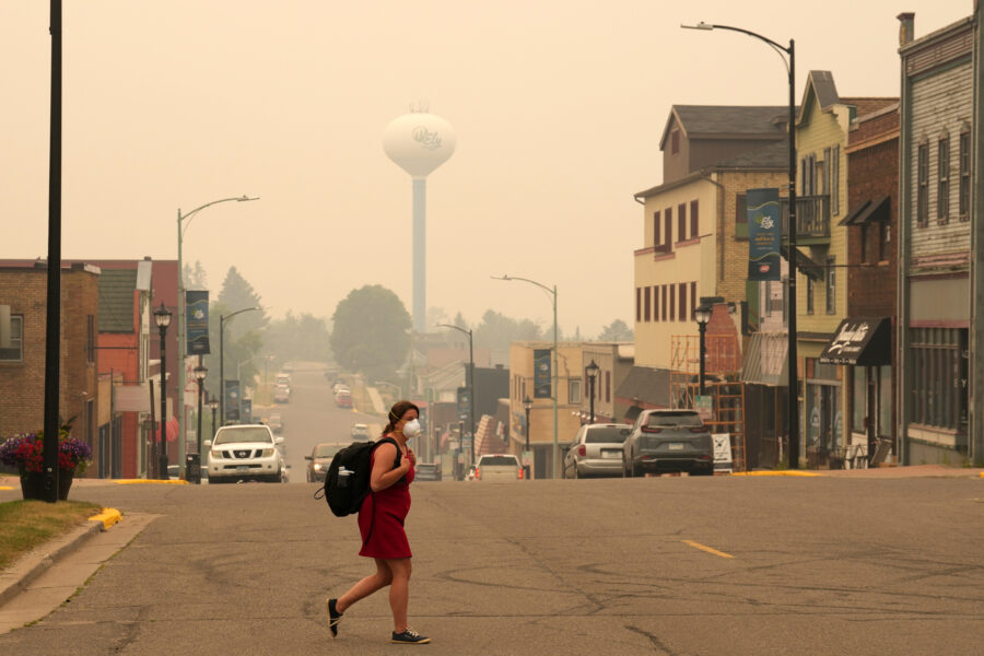 A pedestrian walks in downtown Ely, Minn., as the air is filled with smoke from multiple wildfires burning in the Boundary Waters Canoe Area Wilderness on July 15. Credit: Anthony Soufflé/The Minnesota Star Tribune via Getty Images