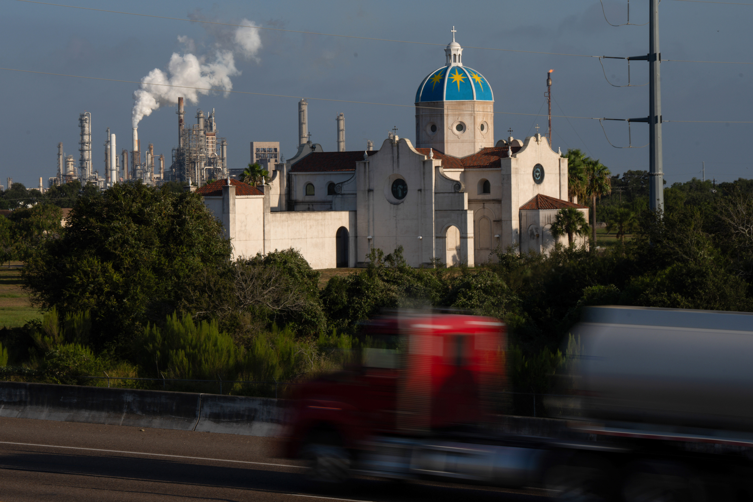 A truck passes Our Lady of Corpus Christi church with Valero’s Corpus Christi refinery in the background on Aug. 23. Credit: Jon Shapley/Inside Climate News