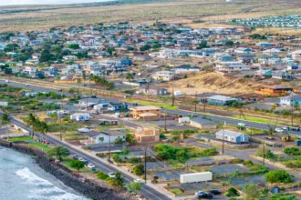An aerial photo shows a portion of Lahaina, Hawaii, near the water. Properties are a mix of homes, houses under construction and empty lots.