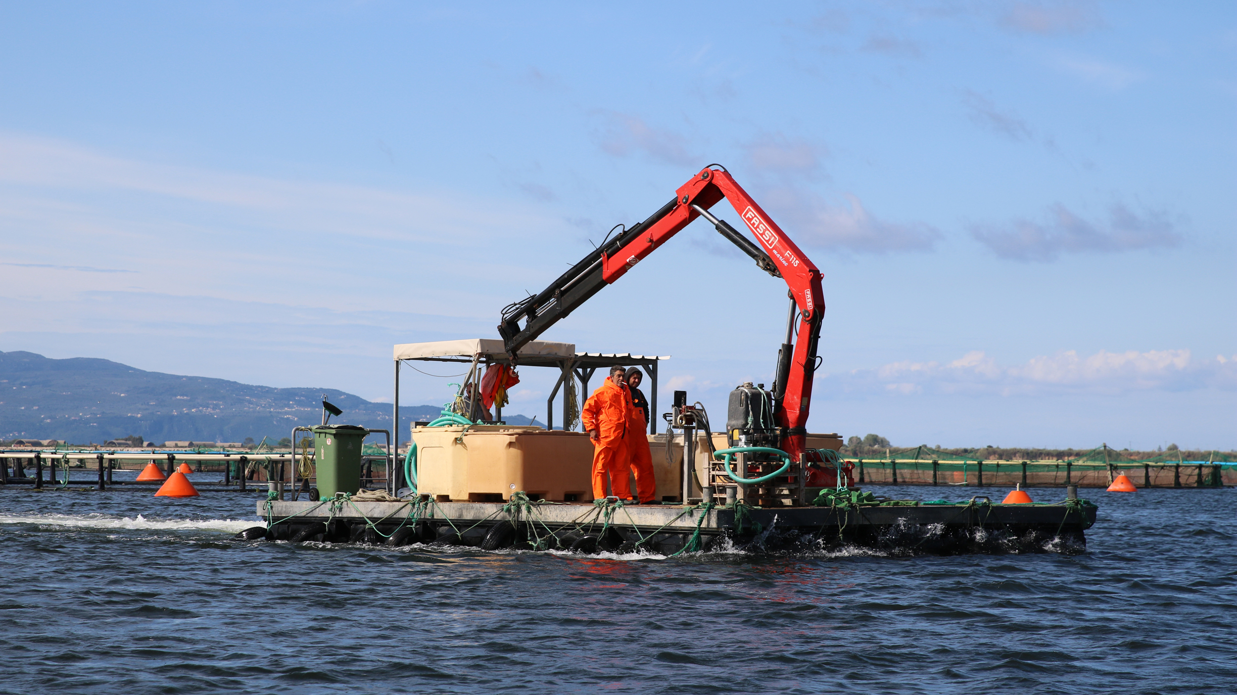 Workers operate a feed barge. Critics argue Greek aquaculture hasn’t created any new jobs in the last 20 years. Credit: Ryan Green/The Outlaw Ocean Project