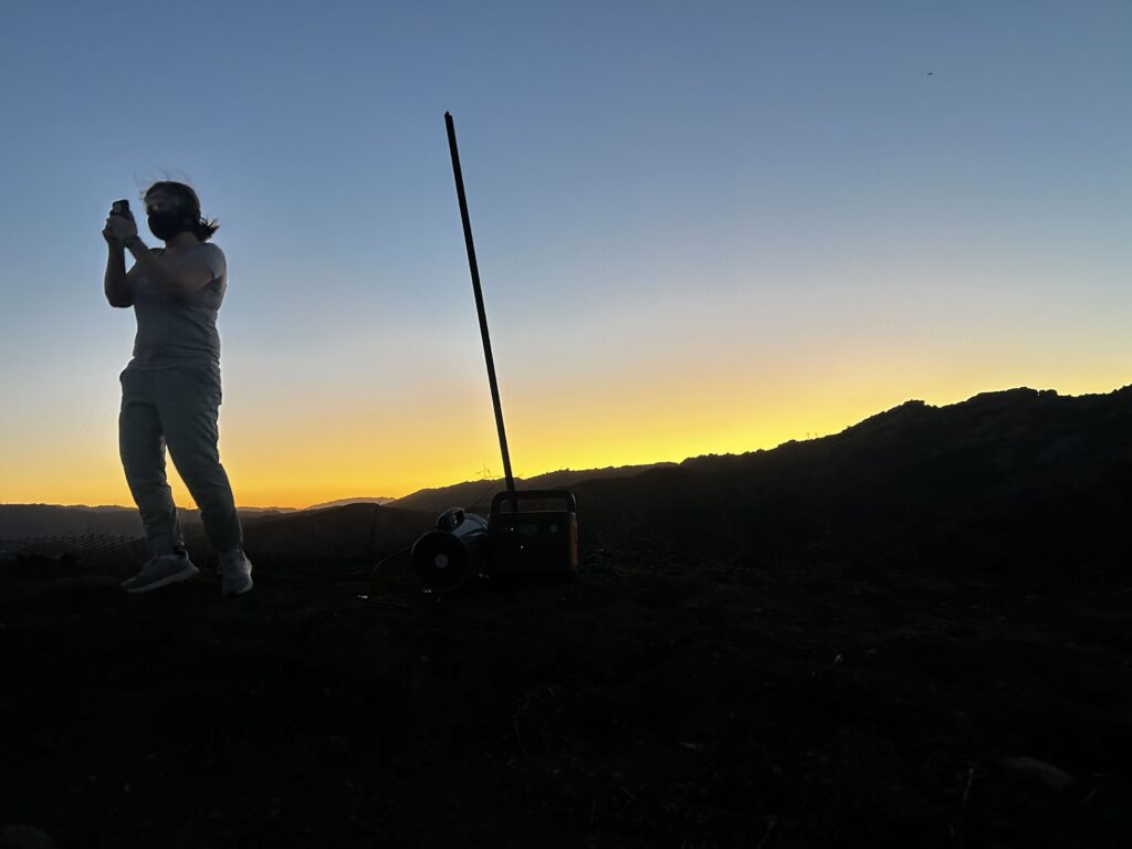 Melissa Bumstead, founder and co-director of Parents Against SSFL, sets up air monitoring equipment near the Santa Susana Field Laboratory site in October 2026. Bumstead, who consulted with scientists, said the equipment is needed due to regulators declining to do additional air monitoring during the demolition of buildings at the closed nuclear facility. Credit: Courtesy of Melissa Bumstead.