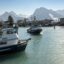 A commercial fishing boat enters the harbor at Valdez, Alaska, with a view of the Chugach mountain range.