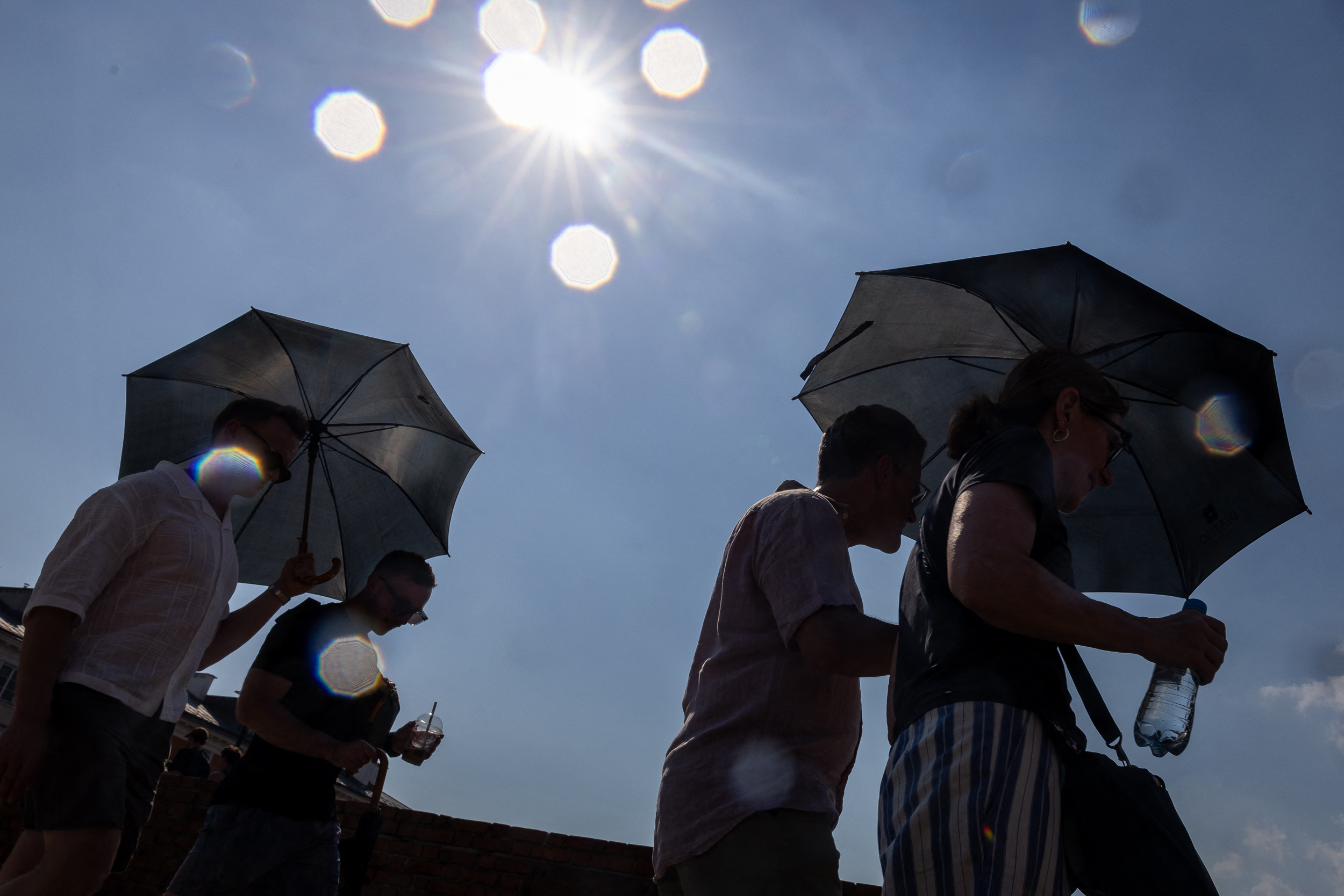 People shelter from the sun under umbrellas in Warsaw’s Old Town as Poland experienced record heat on June 28. Credit: Wojtek Radwanski/AFP via Getty Images