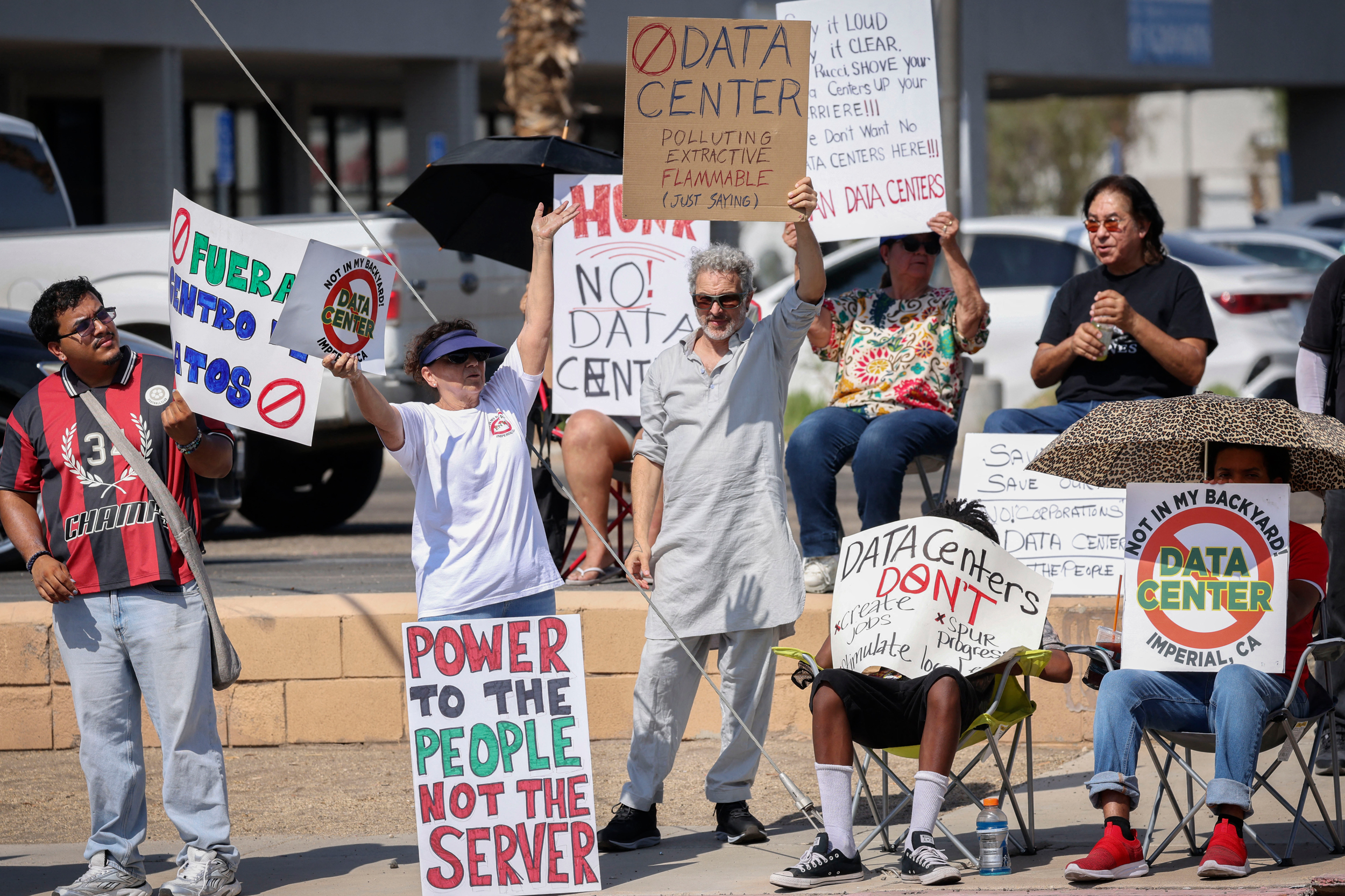 Demonstrators wave signs during a protest against AI data center development in rural Imperial, Calif., on July 18. Credit: Sandy Huffaker/AFP via Getty Images