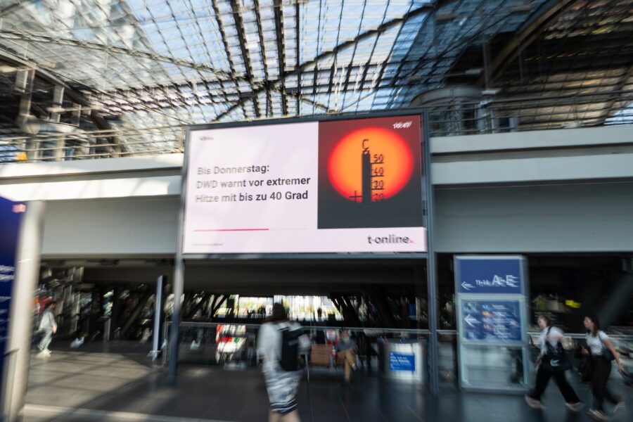 Passengers walk past a heat-warning display at the main train station in Berlin, Germany's capital, on July 30, 2026 / Getty Images