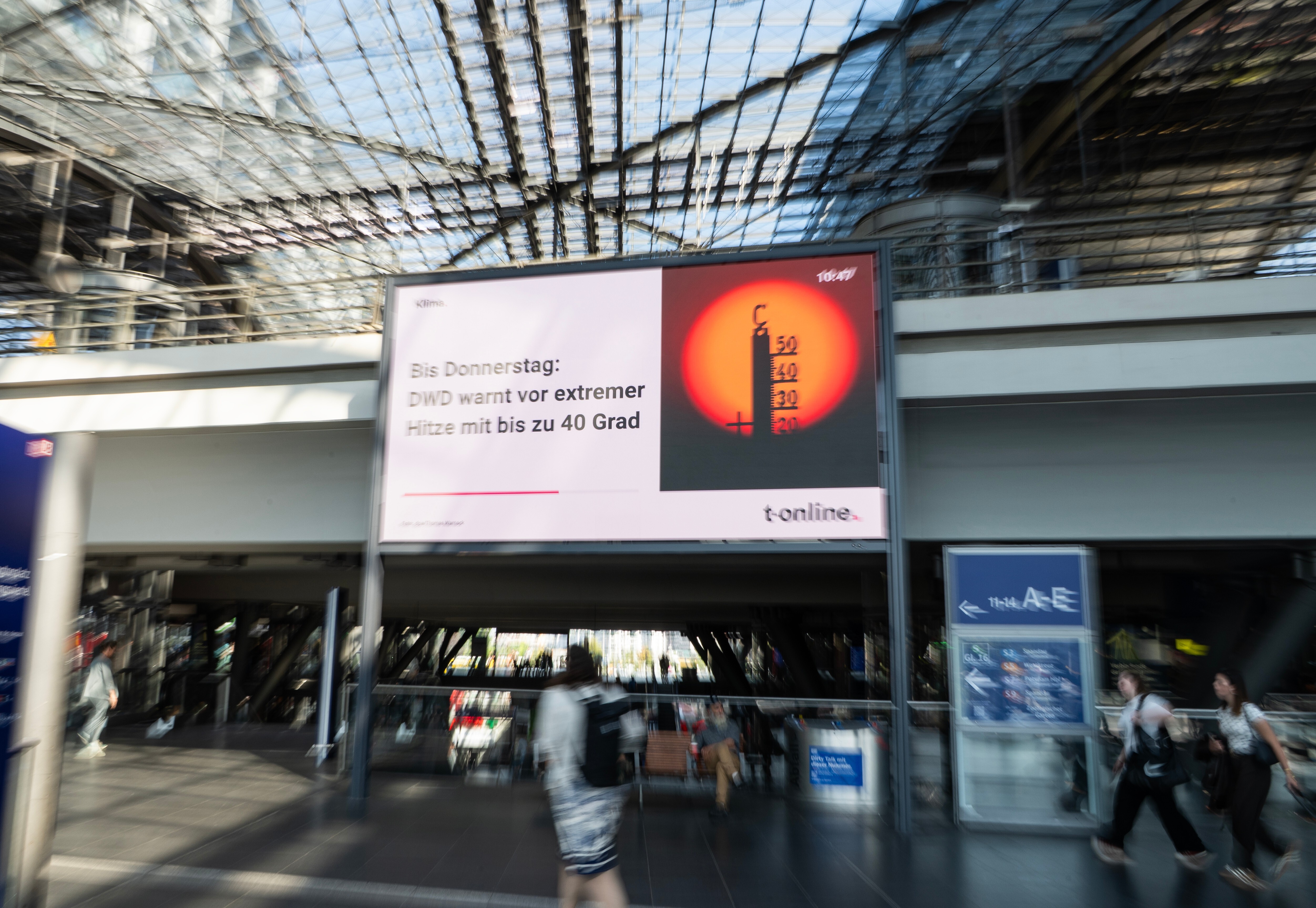 Passengers walk past a heat-warning display at the main train station in Berlin, Germany's capital, on July 30, 2026 / Getty Images