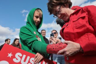 U.S. Sen. Susan Collins signs the cast of Finley Swartz at a Maine fairgrounds. Swartz is holding a Susan Collins sign.
