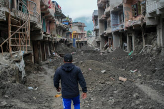 A man walks past debris from houses damaged by devastating floods in Devighat, in Nepal's Nuwakot district, on Oct. 15, 2026.