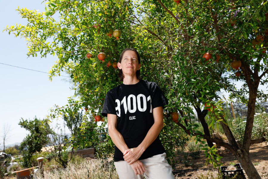 Sylvie Andrews stands under a pomegranate tree on her property devastated by the Eaton Fire in Altadena, Calif. Credit: Carlin Stiehl/Inside Climate News