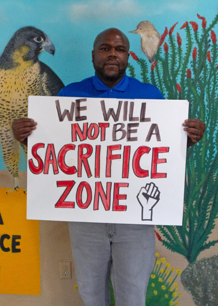 William Cooper, founder of The Becoming Project, holds a sign reading “We Will Not Be a Sacrifice Zone” in the organization’s office in Calipatria, Calif. Credit: Carla Samon Ros/CJI